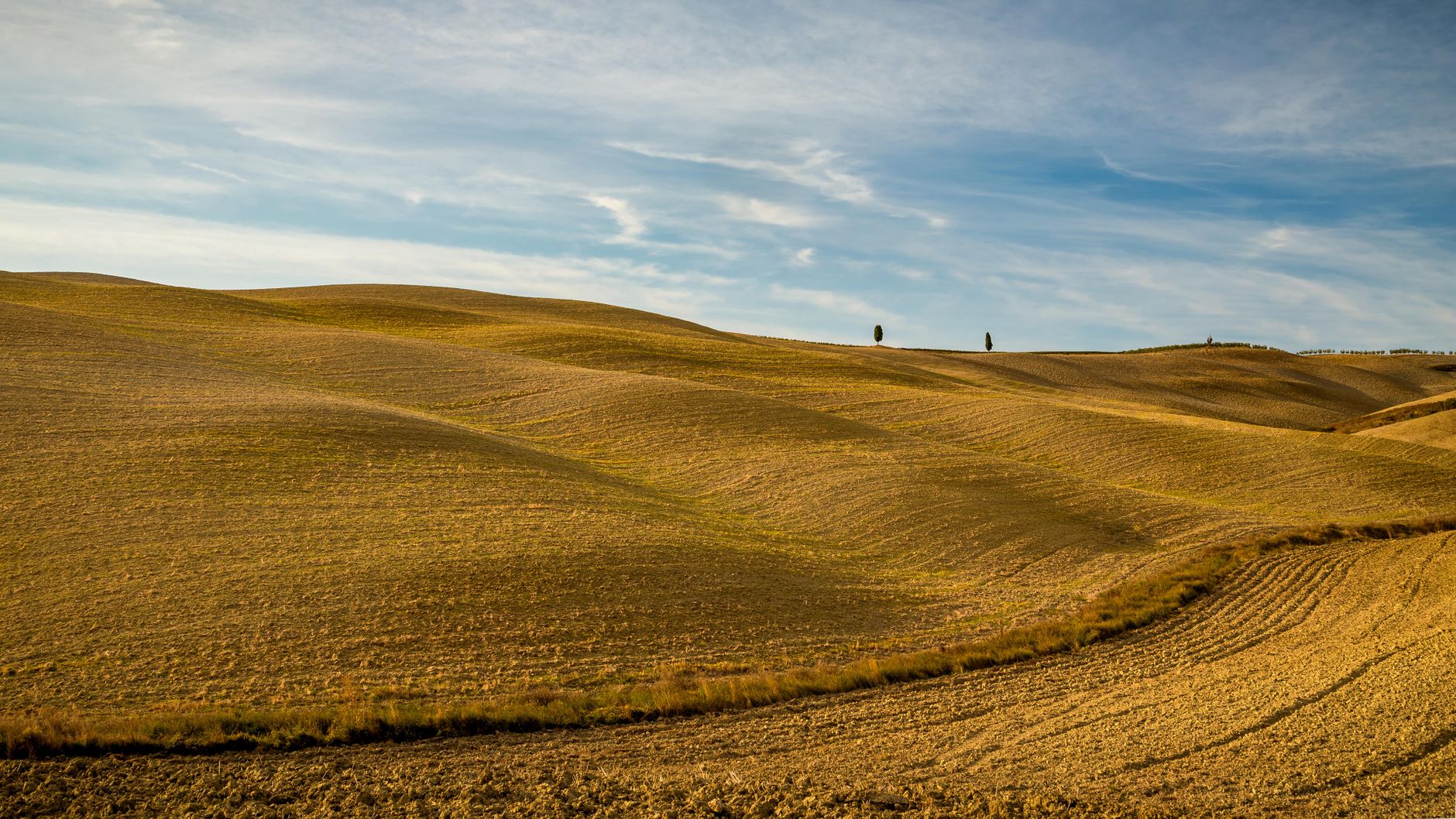 Breathtaking view of Tuscany's rolling hills under a golden sunset sky. Perfect for nature lovers.