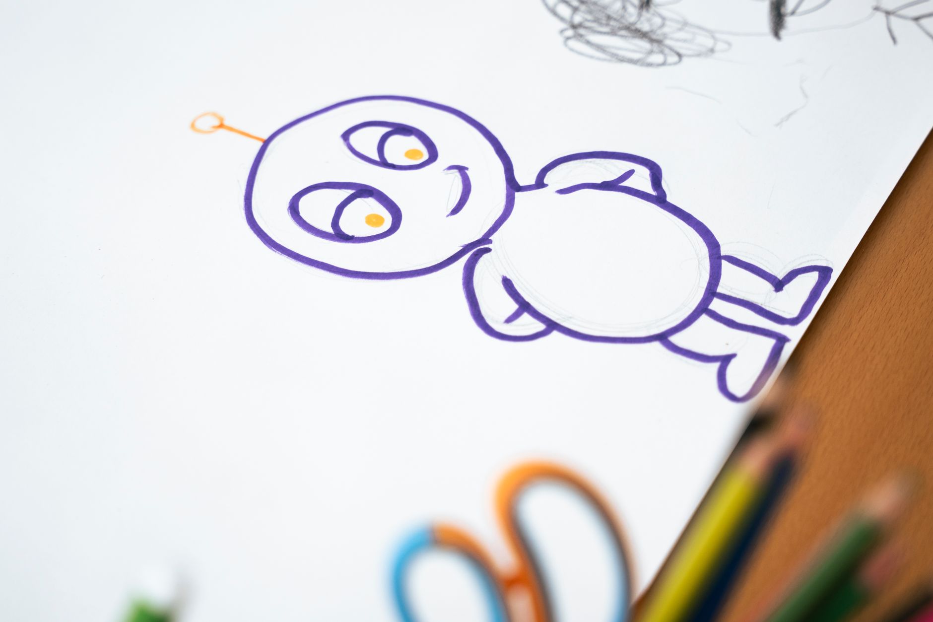 Colorful cartoon character sketch on paper with colored pencils on the side.