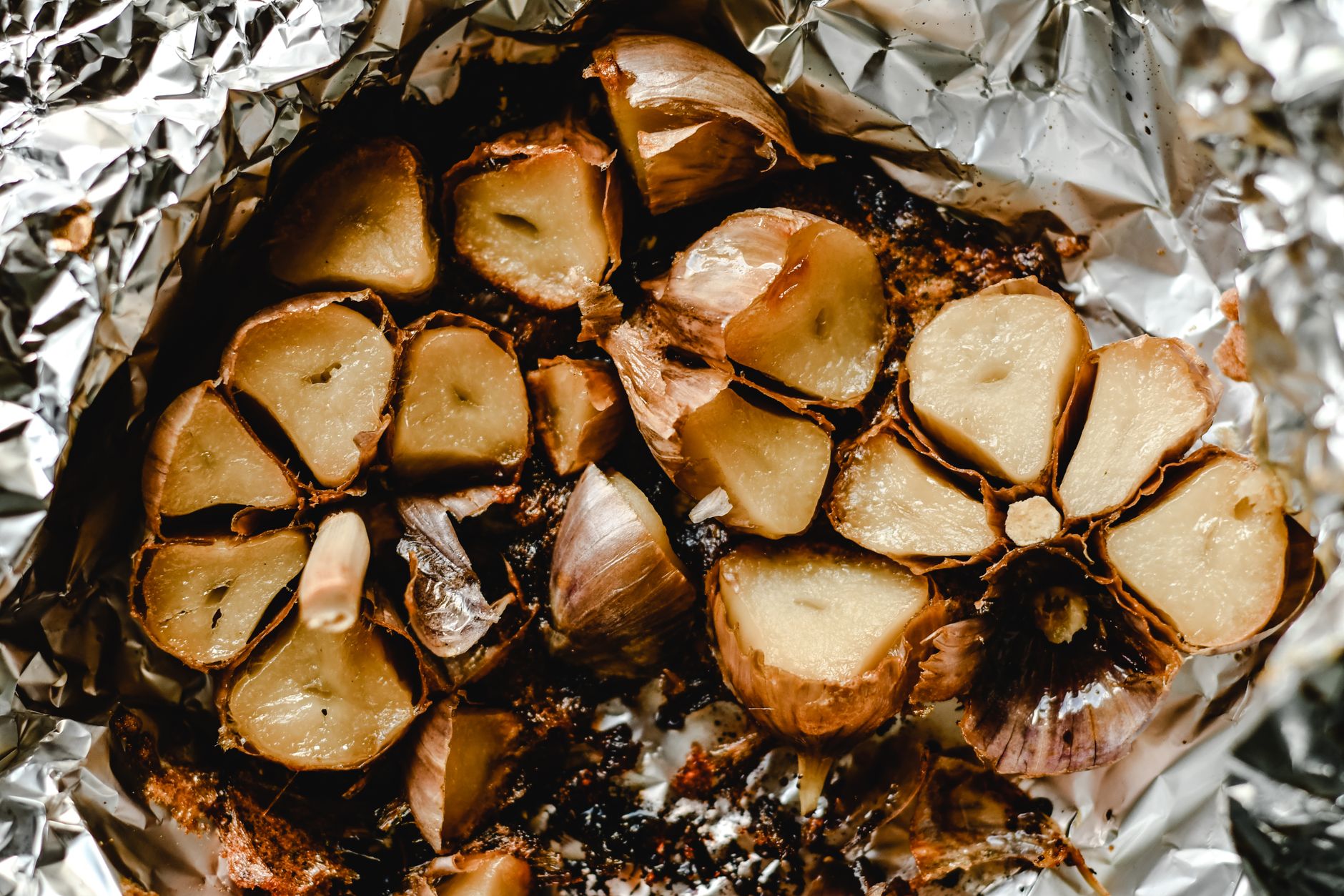Detailed image of roasted garlic cloves in foil, showcasing textures and browning.