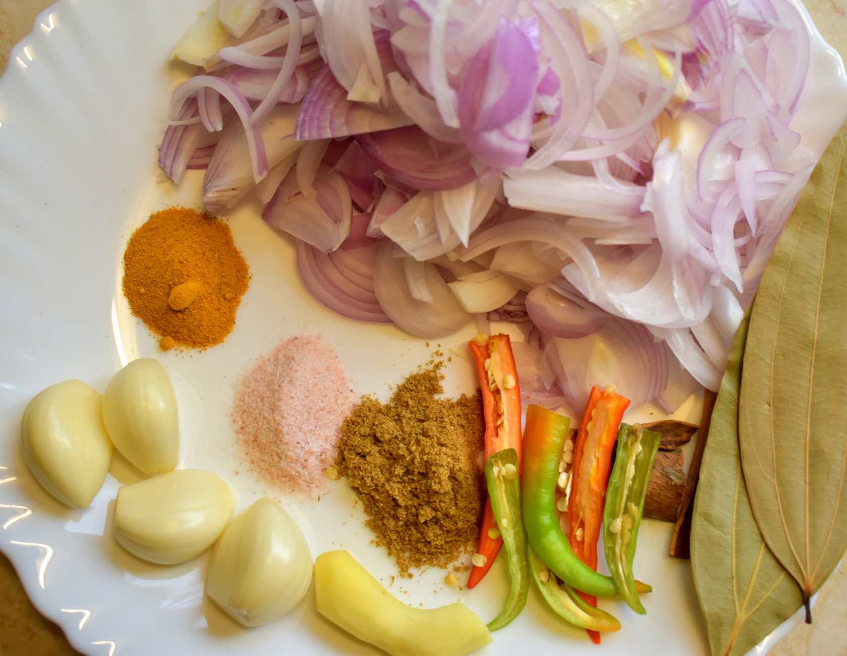 A colorful arrangement of onions, garlic, turmeric, and more on a plate, perfect for flavorful home cooking.